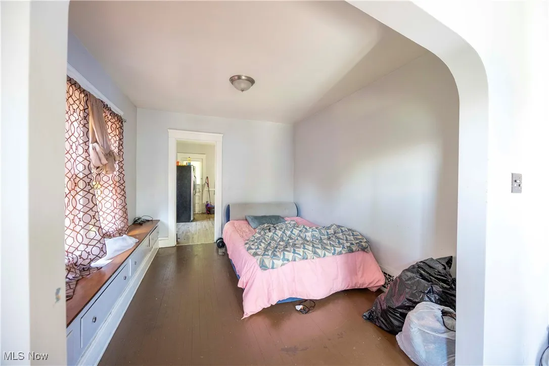 Bedroom with arched walkways and wood finished floors