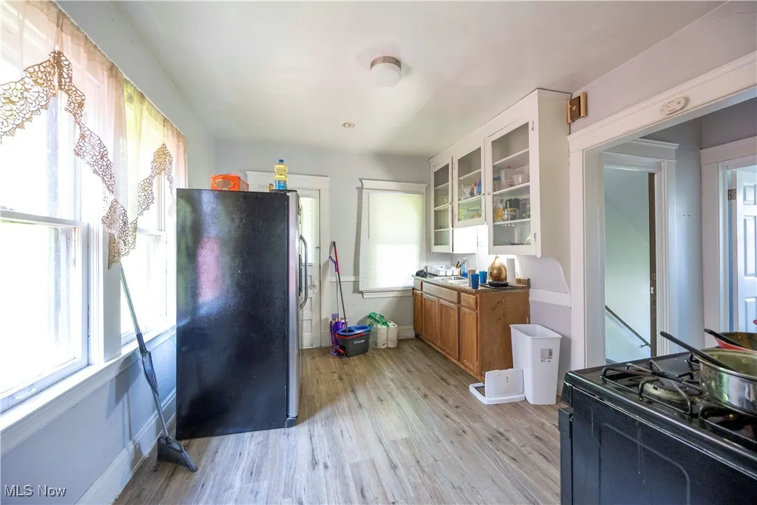 Kitchen with freestanding refrigerator, brown cabinets, light wood-type flooring, and healthy amount of natural light