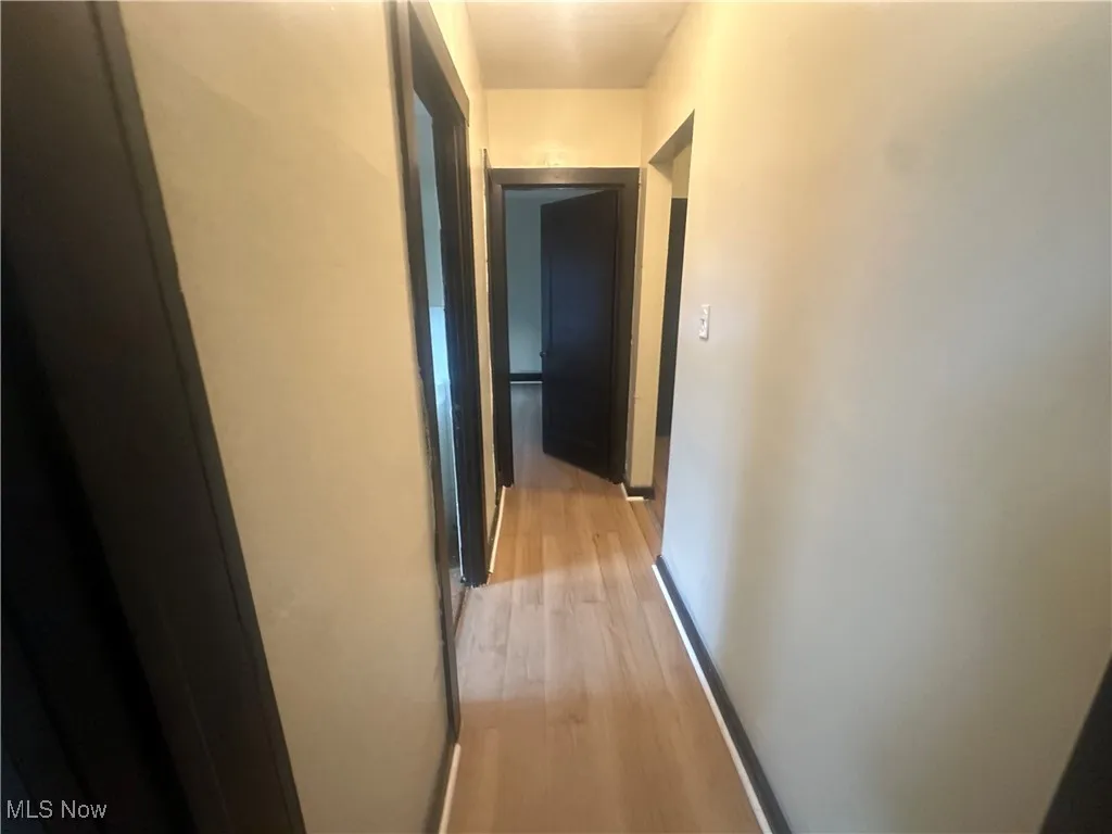 Hallway with light wood-style floors and baseboards