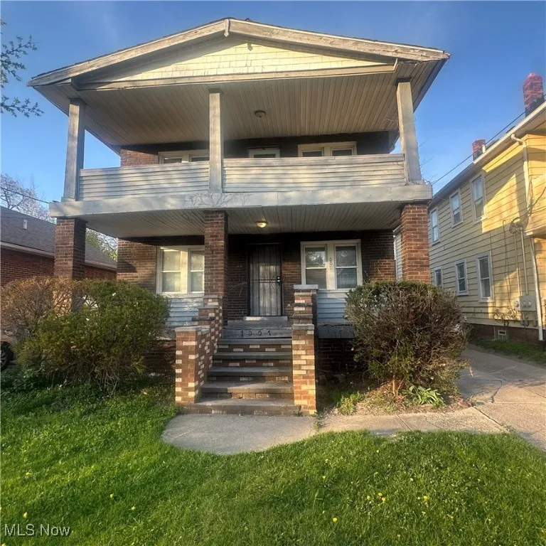 View of front facade with a porch, brick siding, and a balcony