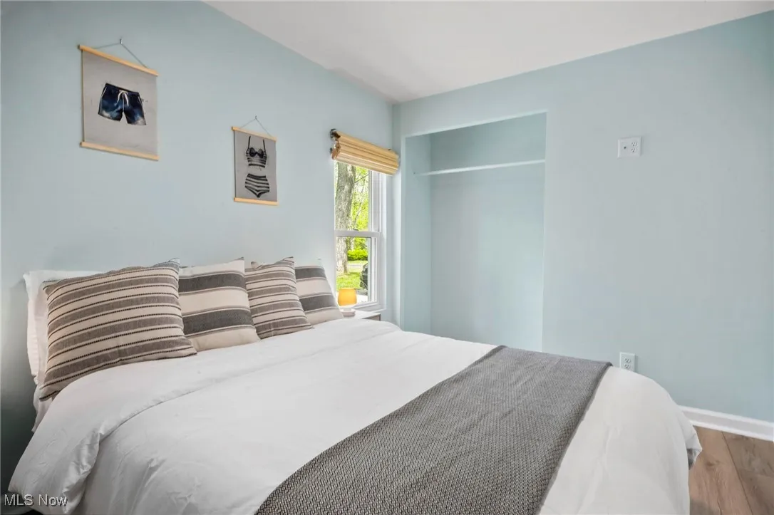 Bedroom with wood finished floors, baseboards, and a closet