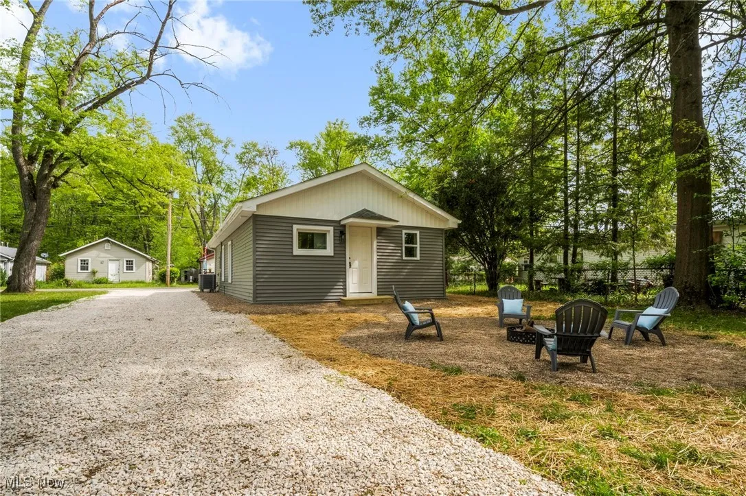 View of front of home with a fire pit, driveway, and central AC unit