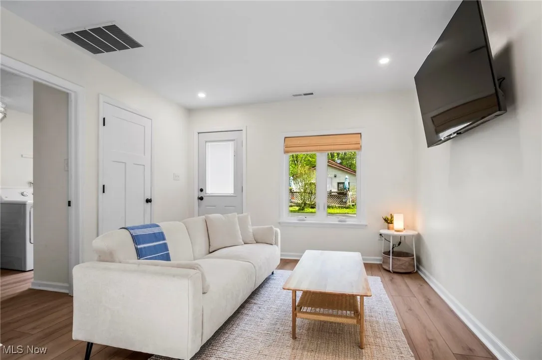 Living room featuring washer / dryer, light wood-style flooring, baseboards, and recessed lighting