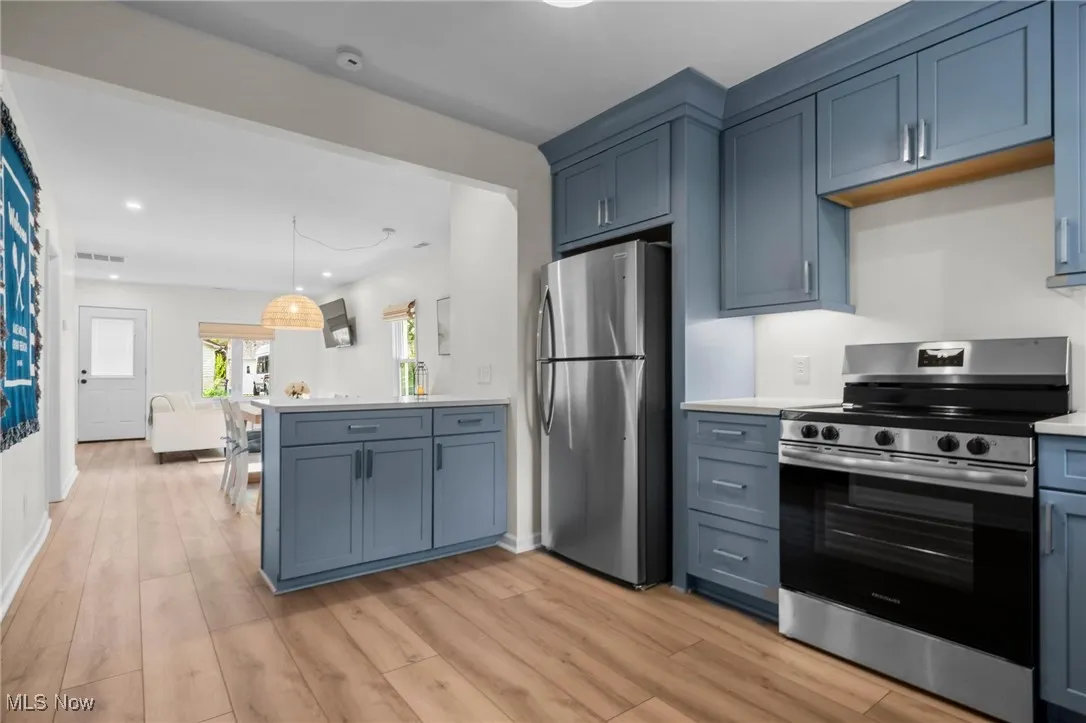 Kitchen with appliances with stainless steel finishes, a peninsula, light countertops, light wood finished floors, and recessed lighting