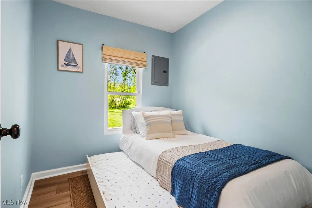 Bedroom featuring wood finished floors, electric panel, and baseboards