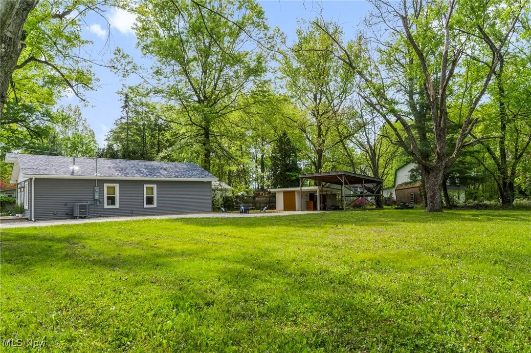 View of grassy yard featuring an outdoor structure and a patio area