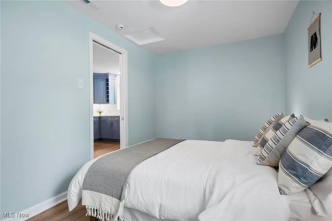 Bedroom with attic access, wood finished floors, ensuite bathroom, and baseboards