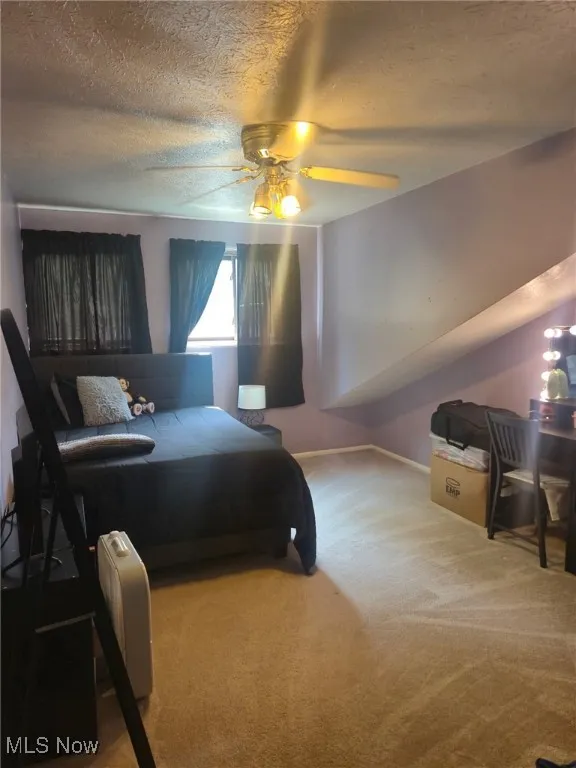 Carpeted bedroom featuring a textured ceiling and ceiling fan