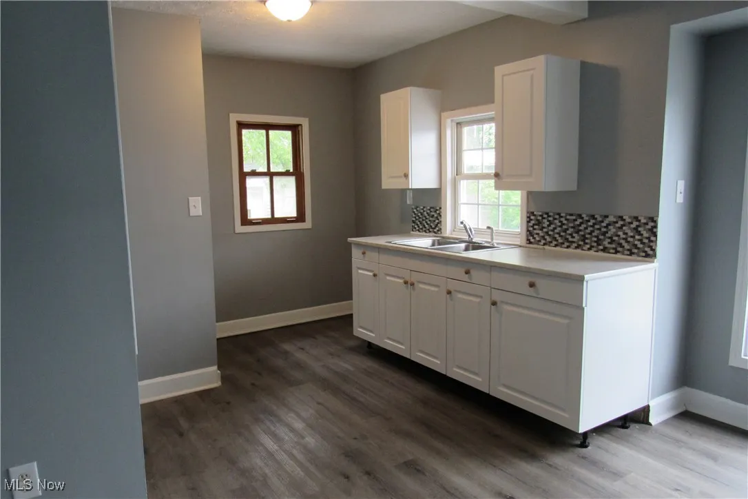 Kitchen featuring a sink, white cabinetry, wood finished floors, and light countertops