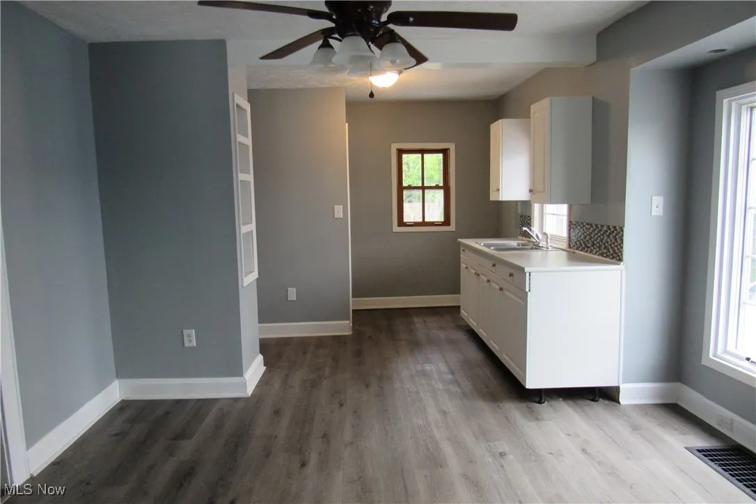 Kitchen featuring white cabinets, a ceiling fan, and wood finished floors