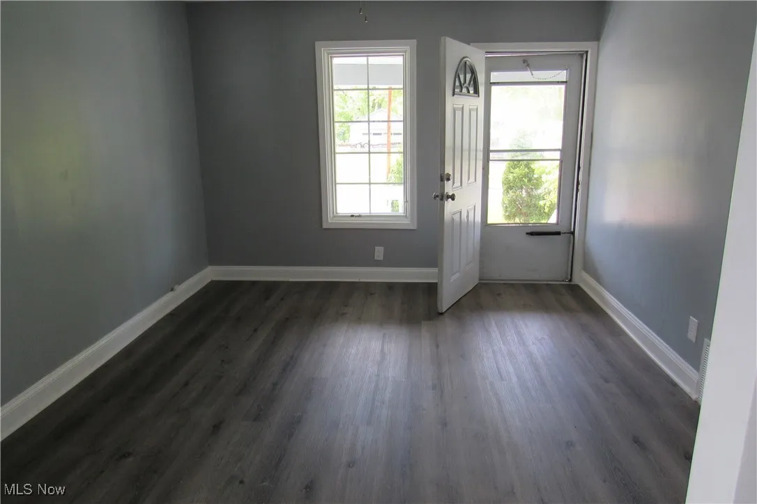 Doorway to outside with dark wood finished floors and baseboards