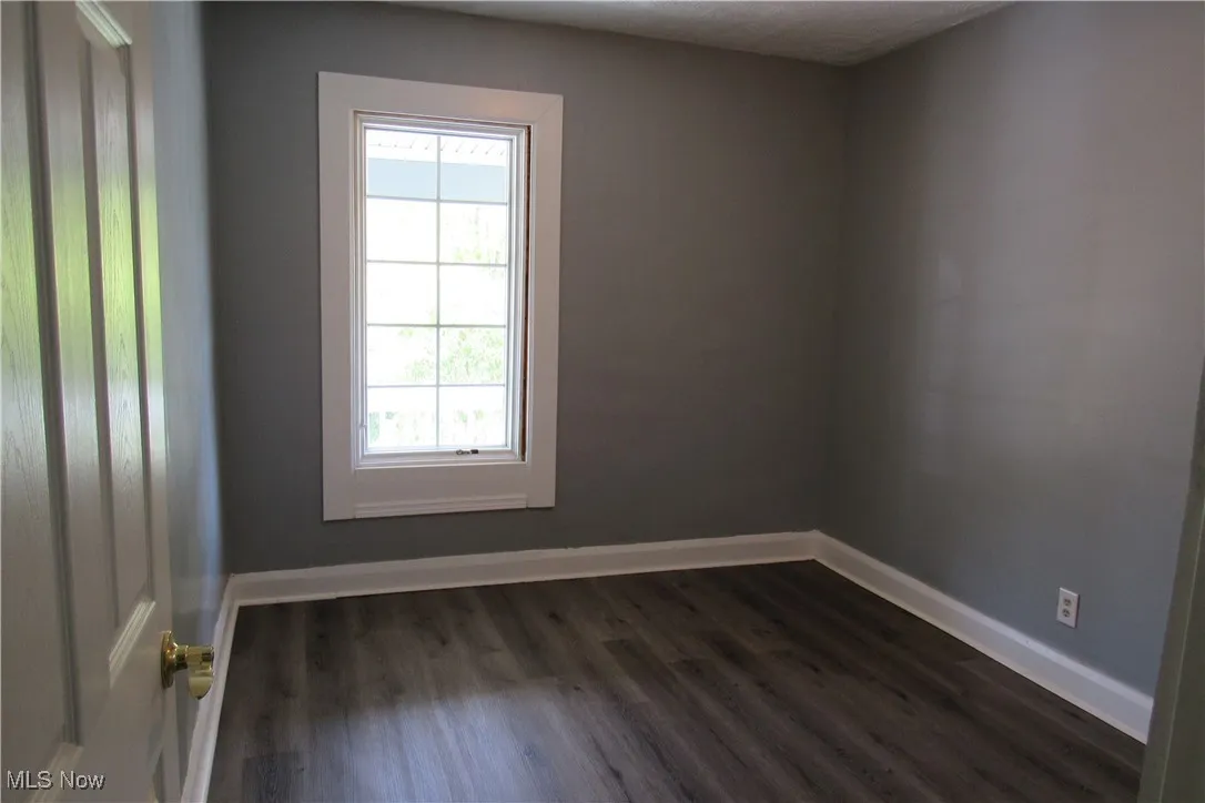 Empty room featuring dark wood-style floors and baseboards