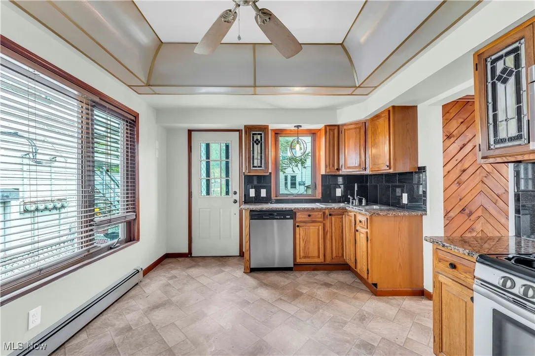 Kitchen featuring stainless steel dishwasher, a baseboard heating unit, tasteful backsplash, range with electric stovetop, and baseboards
