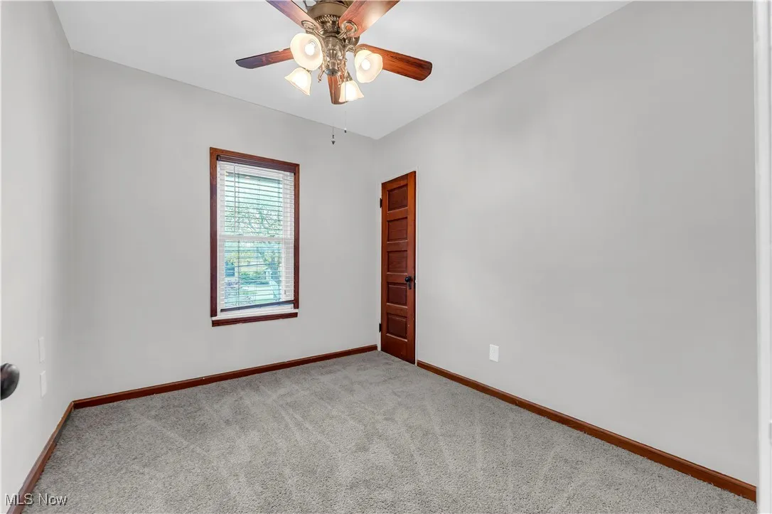 Carpeted spare room with baseboards and a ceiling fan