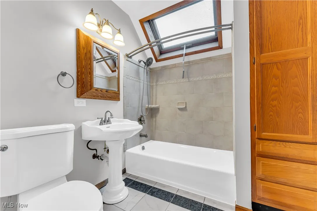 Bathroom featuring toilet, washtub / shower combination, and a skylight