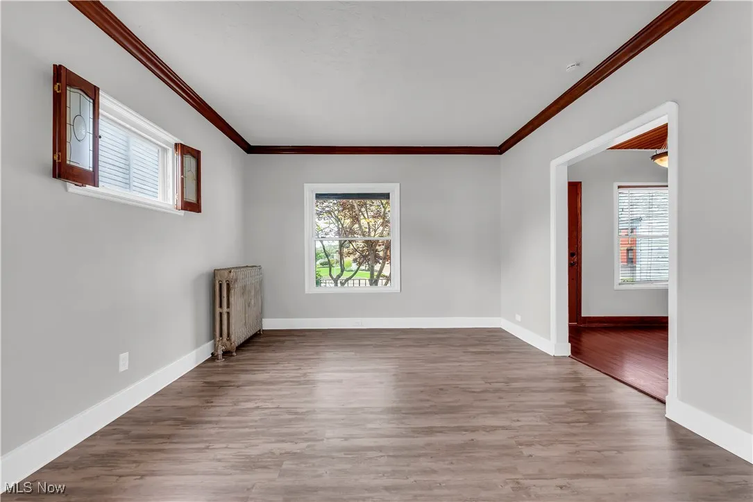Unfurnished room with radiator, ornamental molding, wood finished floors, and baseboards