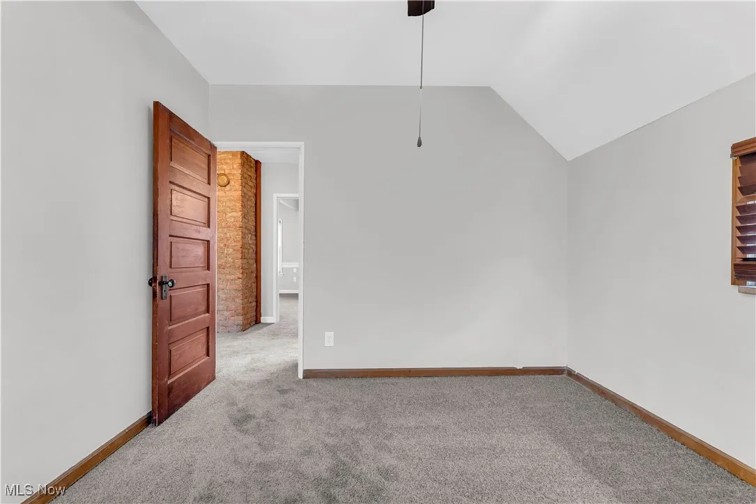 Carpeted spare room with lofted ceiling and baseboards