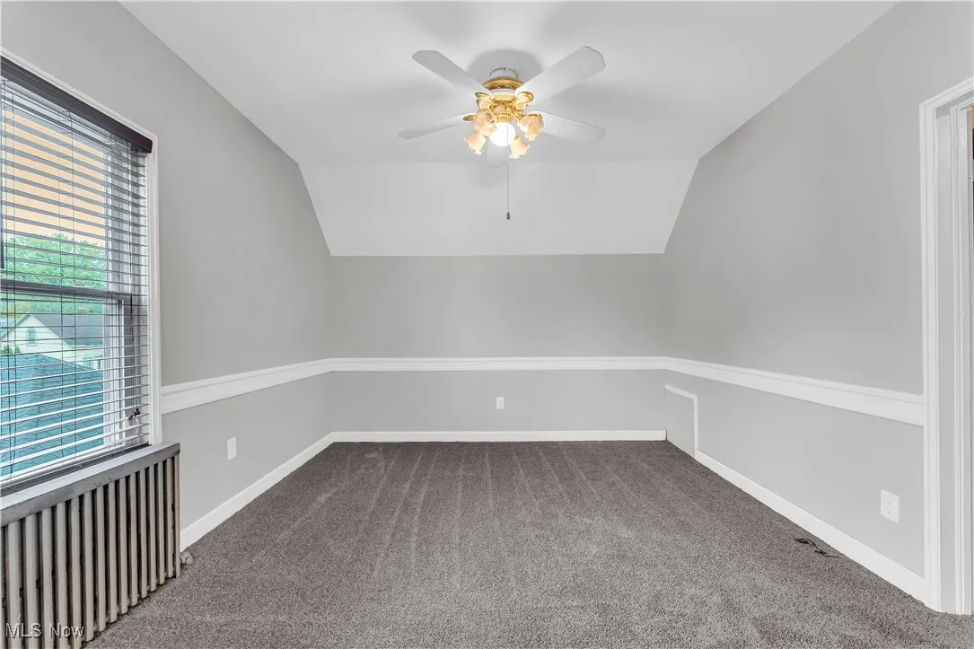 Bonus room featuring radiator, vaulted ceiling, a ceiling fan, carpet flooring, and baseboards
