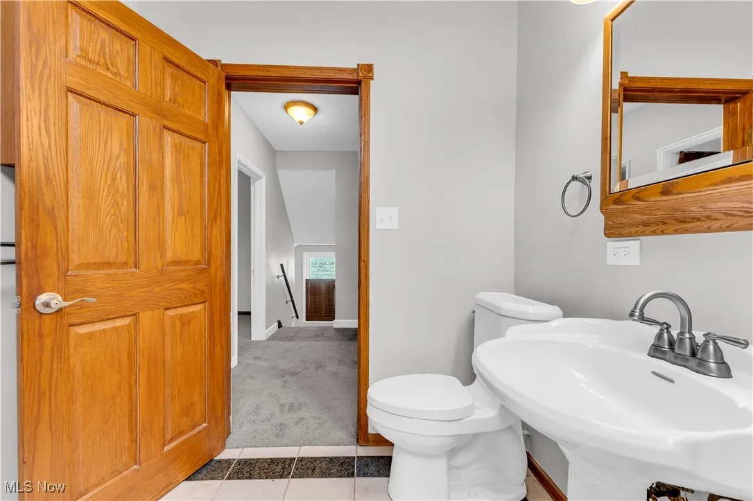 Half bathroom with a sink, tile patterned flooring, toilet, and baseboards