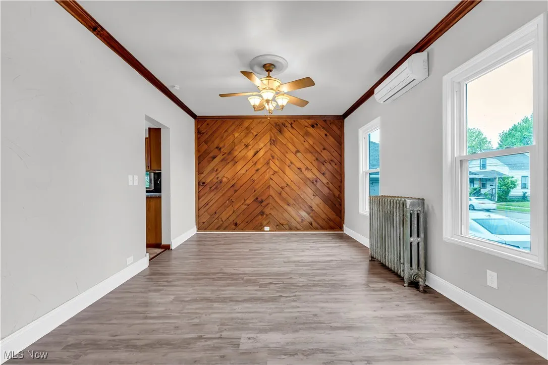Spare room featuring radiator, a ceiling fan, crown molding, an AC wall unit, and baseboards
