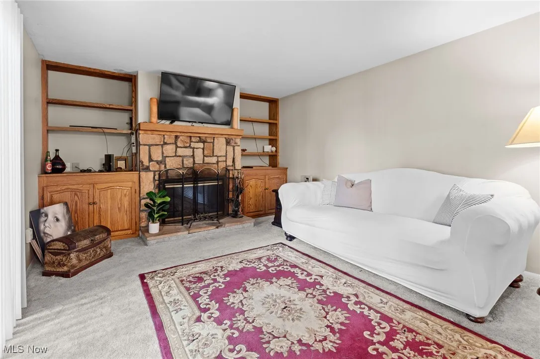 Living area with carpet flooring and a stone fireplace