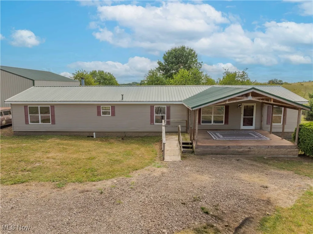 Back of house with covered porch, a metal roof, and a yard