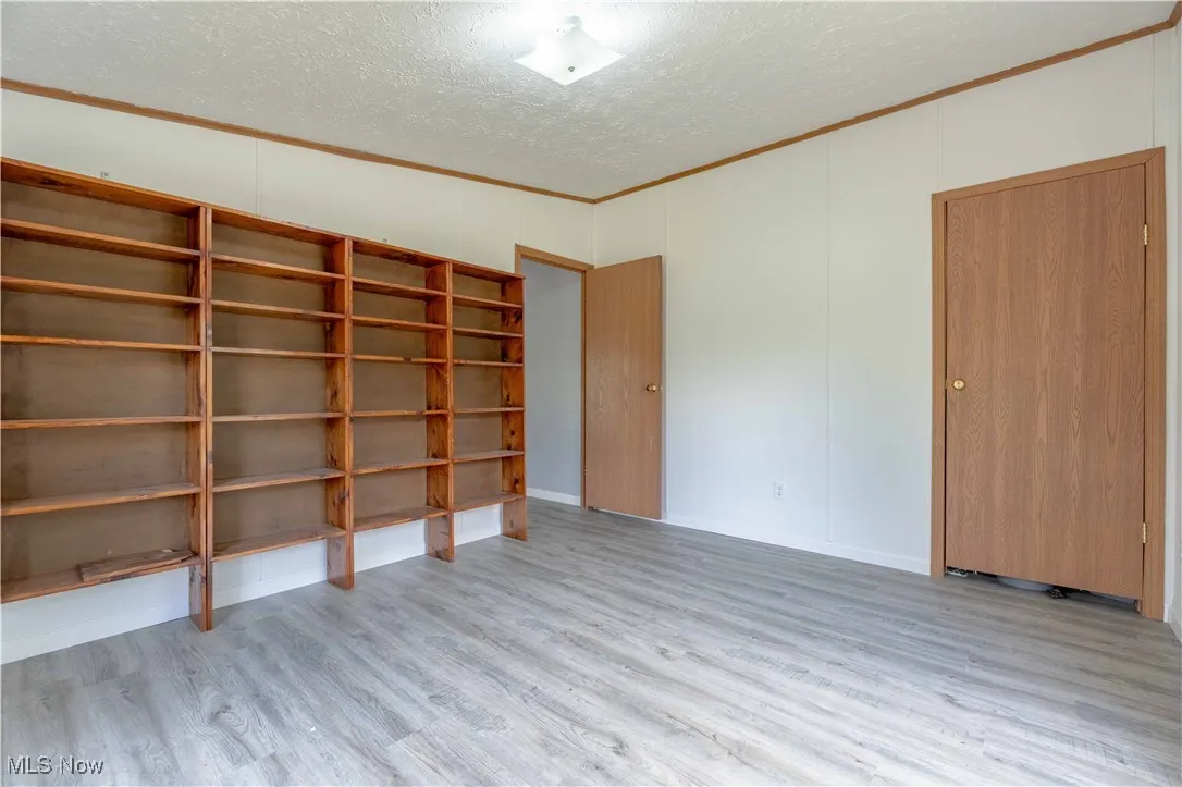 Spare room with crown molding, a textured ceiling, and light wood-style flooring