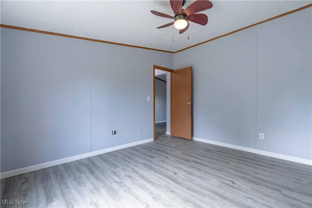 Spare room with crown molding, wood finished floors, and ceiling fan