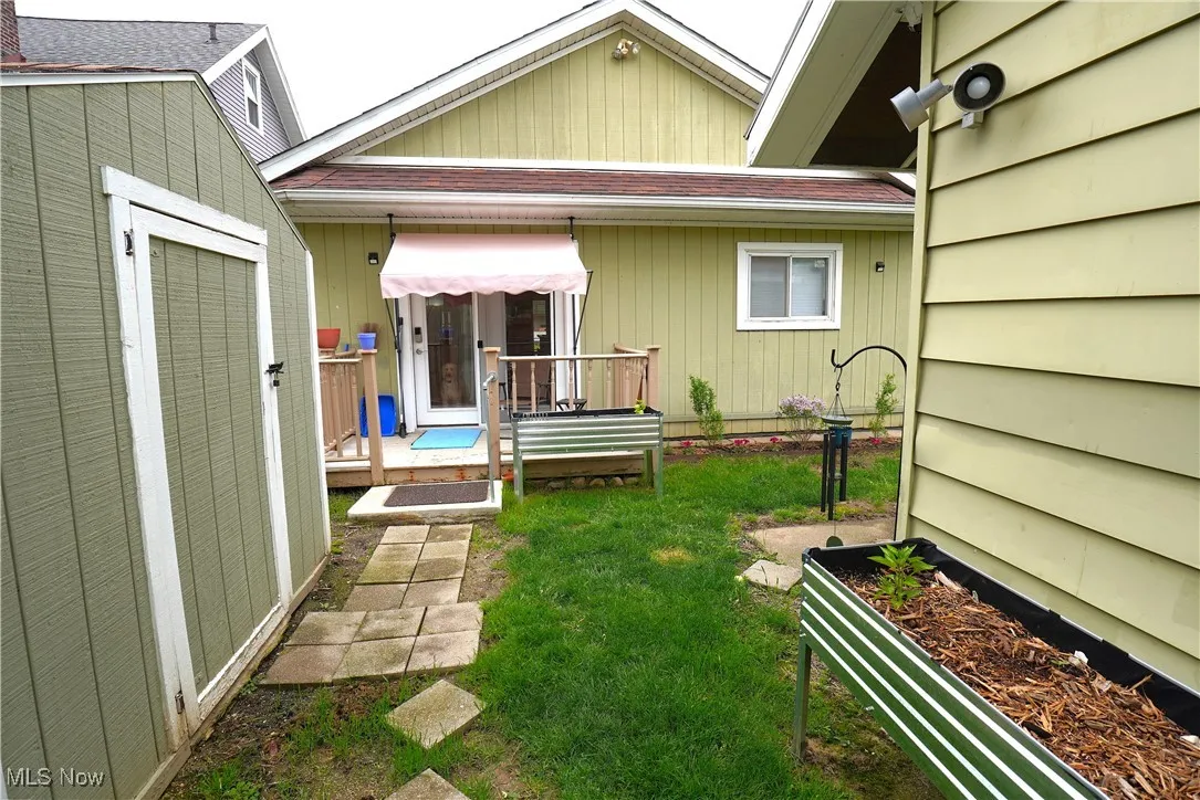 Back of property featuring a lawn, a shingled roof, an outbuilding, and a shed