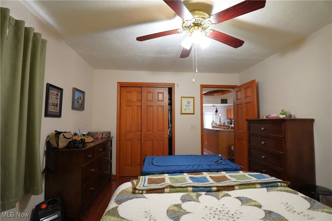 Bedroom featuring dark wood-style floors, a closet, and ceiling fan