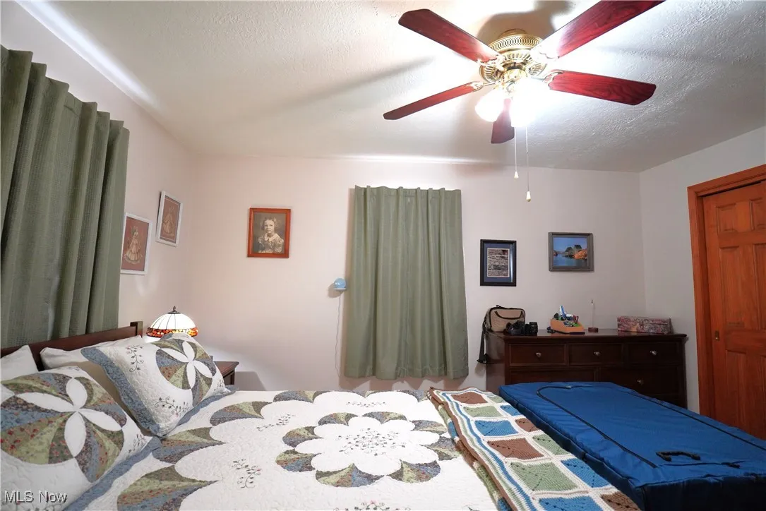 Bedroom featuring a ceiling fan and a textured ceiling