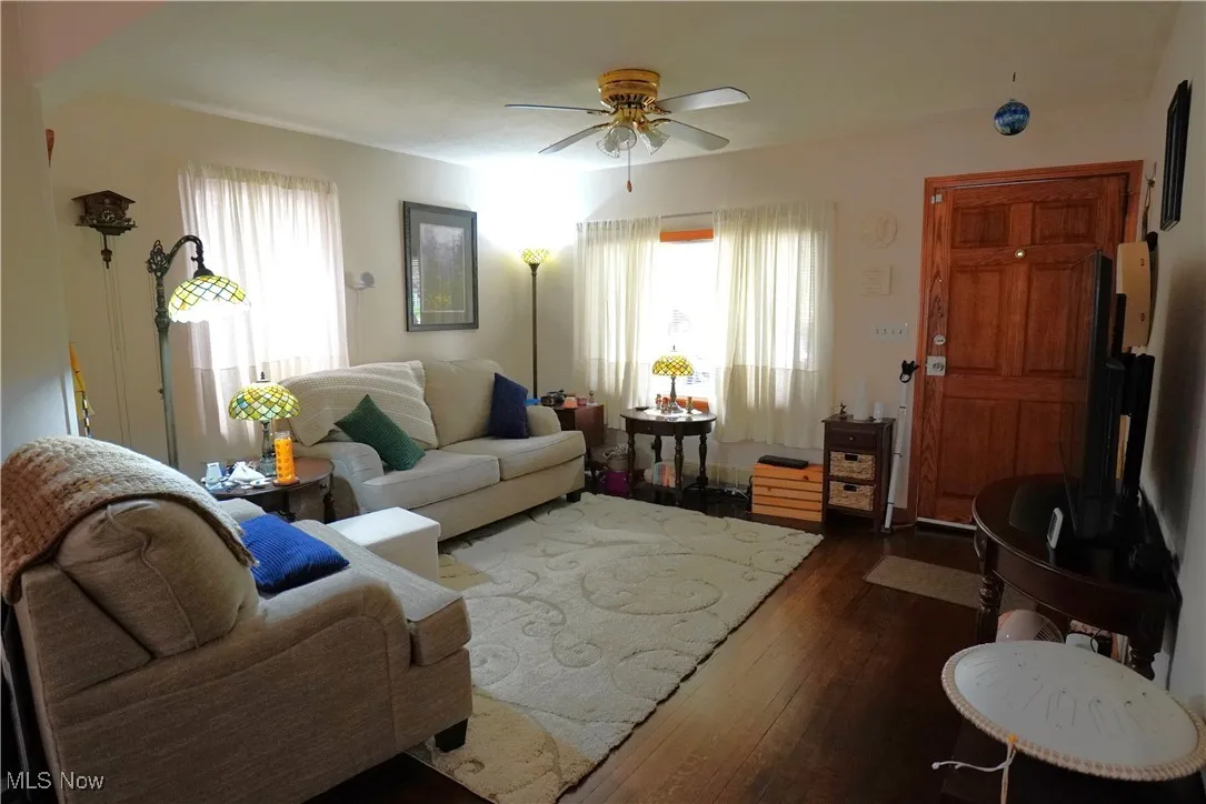 Living area featuring dark wood-style flooring and a ceiling fan