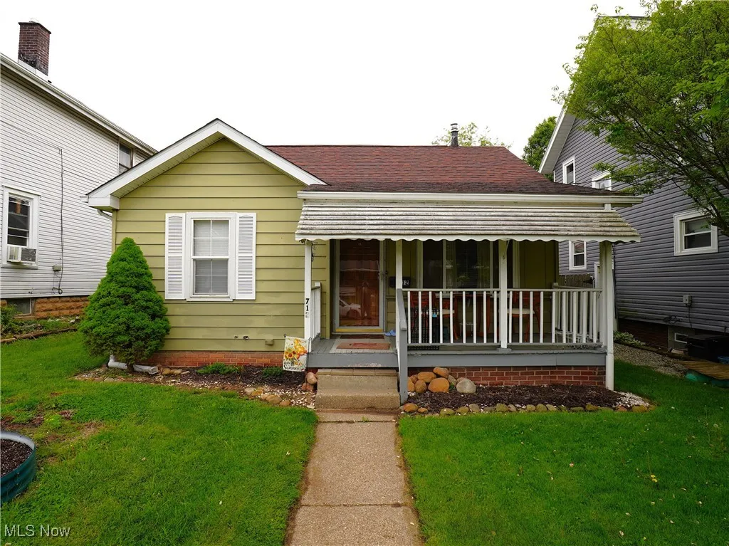 Bungalow-style house featuring a porch, a front yard, roof with shingles, and cooling unit