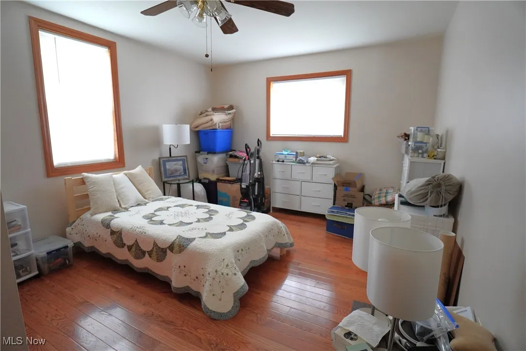 Bedroom featuring multiple windows, hardwood / wood-style flooring, and ceiling fan