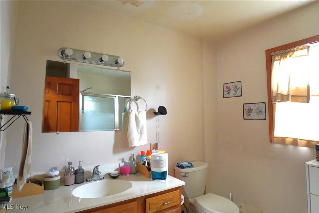 Bathroom with vanity, toilet, and a shower with door