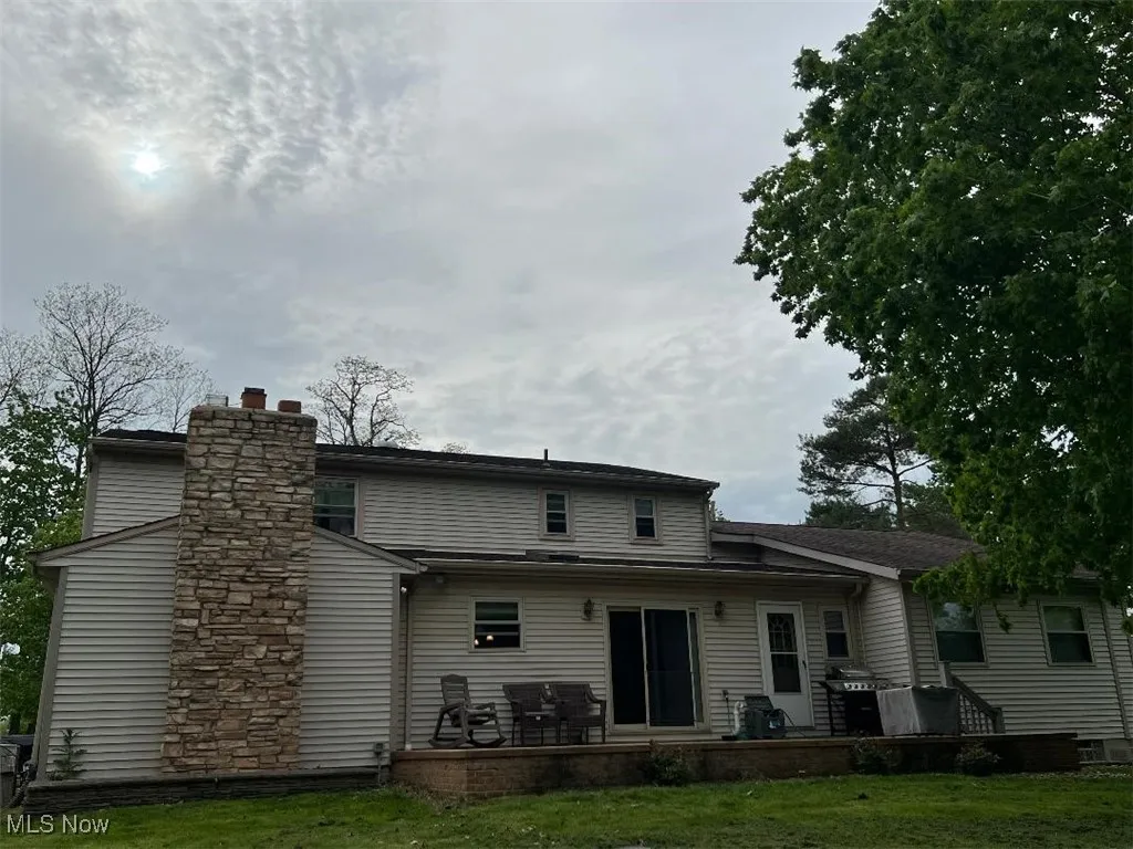 Back of property featuring a yard, a chimney, and a patio area