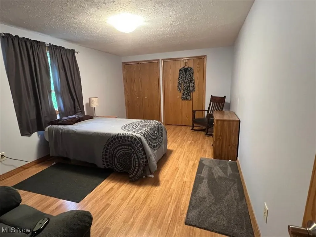 Bedroom featuring light wood-type flooring, a textured ceiling, and double closets