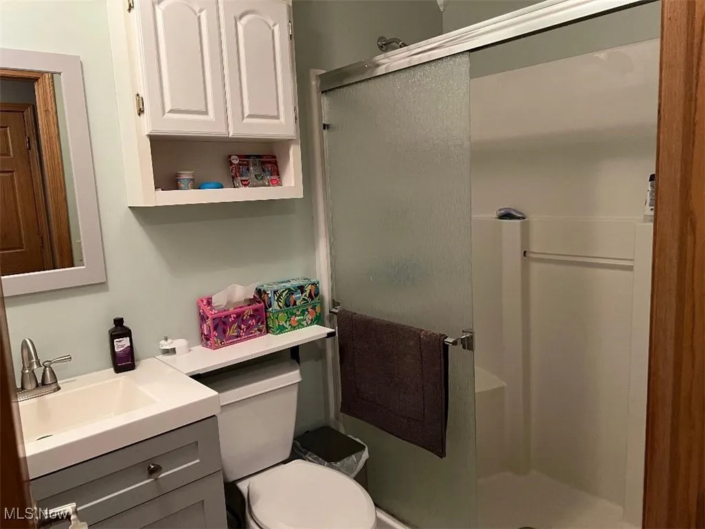 1st-Floor Full bath featuring a shower stall, vanity, and toilet