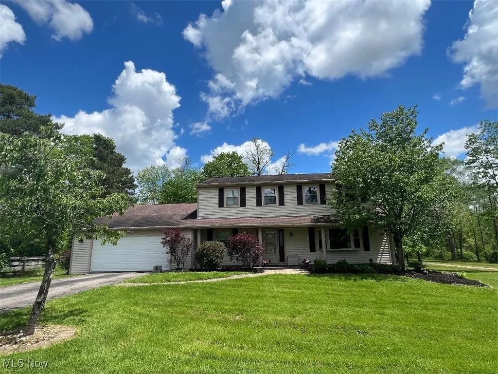 View of front facade featuring asphalt driveway, a front lawn, an attached garage, and covered porch
