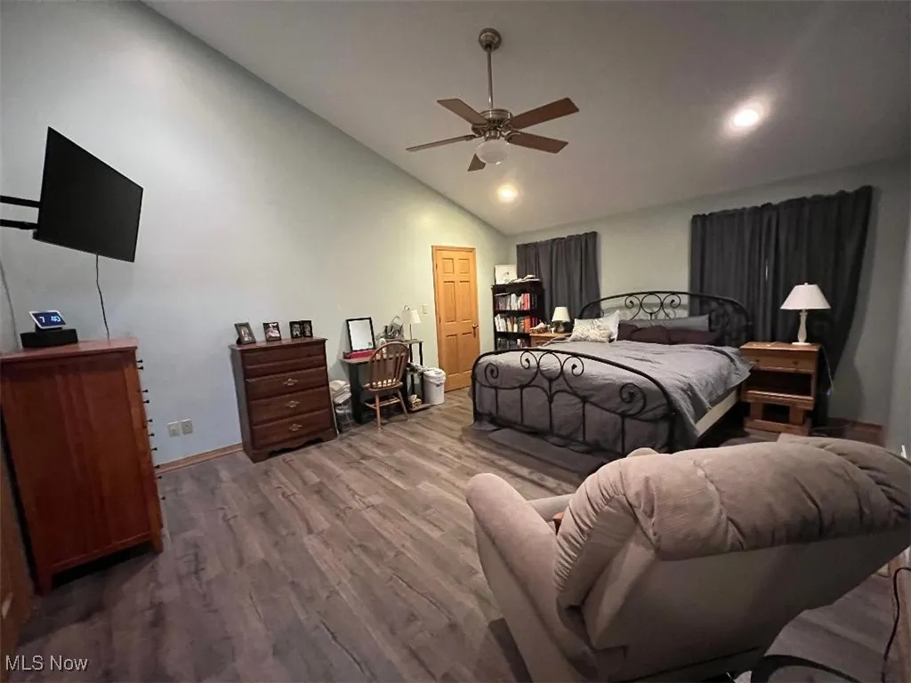 Primary Bedroom with laminate floors, baseboards, a ceiling fan, and high vaulted ceiling