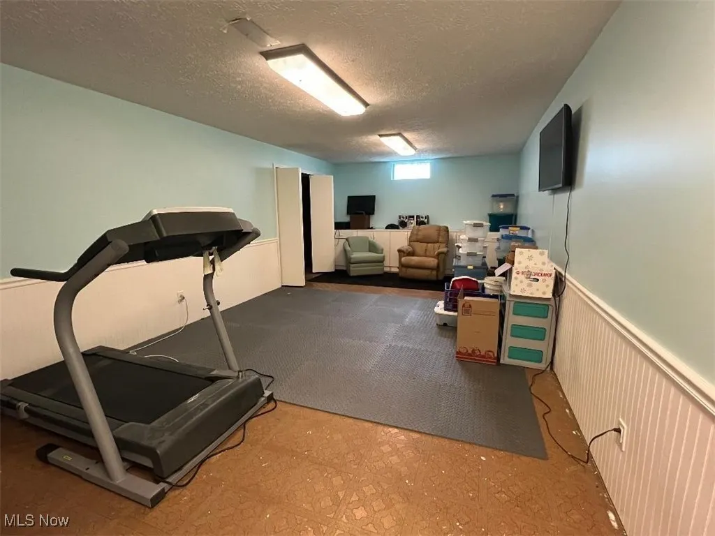 Rec Room with a textured ceiling, beadboard and glass block windows.  White cabinetry at the far end of the room will stay for new owners.