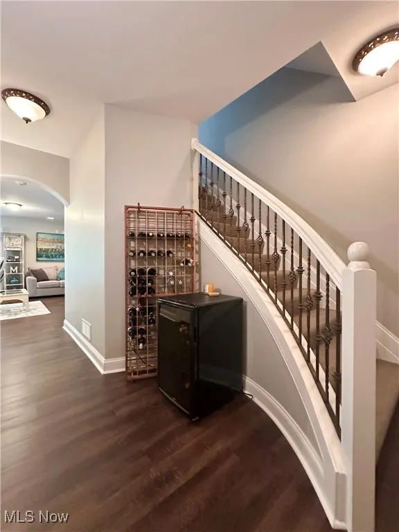 Staircase featuring wood finished floors, baseboards, and arched walkways