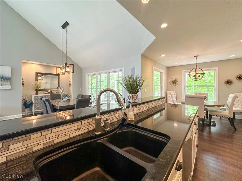 Kitchen with a sink, a chandelier, recessed lighting, hanging light fixtures, and dark wood finished floors