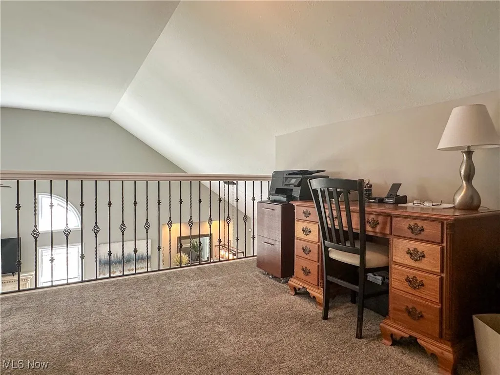 Carpeted office featuring vaulted ceiling