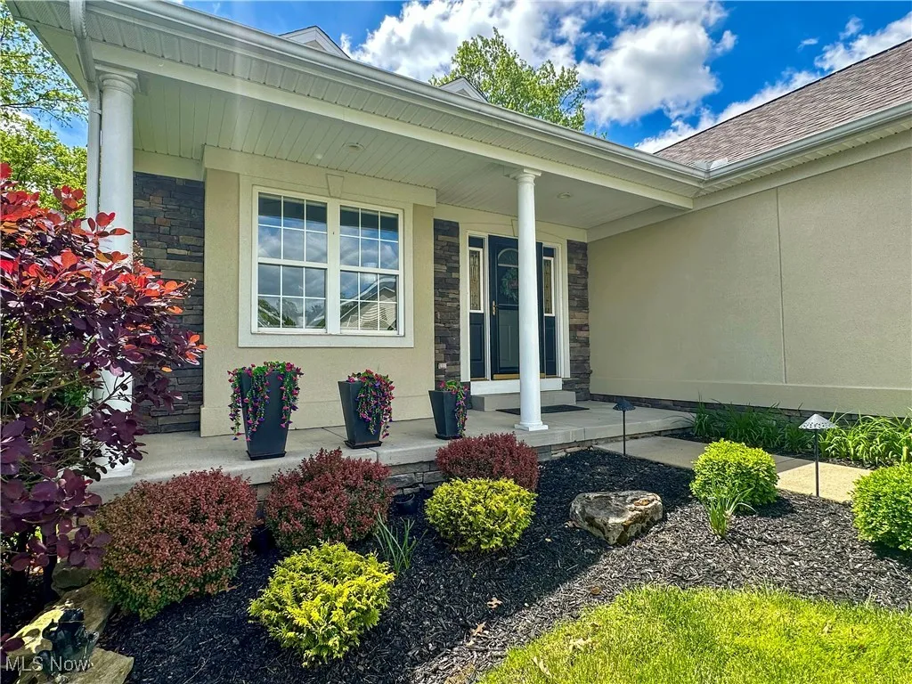 Entrance to property featuring a porch, stone siding, roof with shingles, and stucco siding