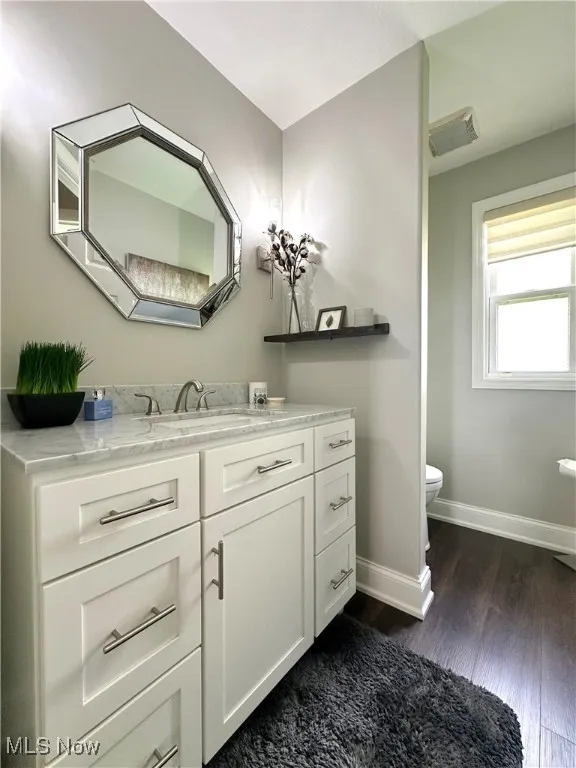 Bathroom with wood finished floors, baseboards, vanity, and toilet