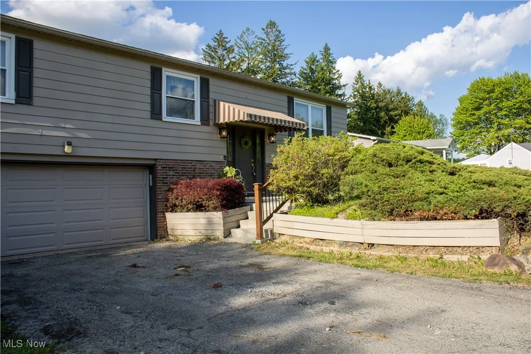 Raised ranch featuring an attached garage, driveway, and brick siding