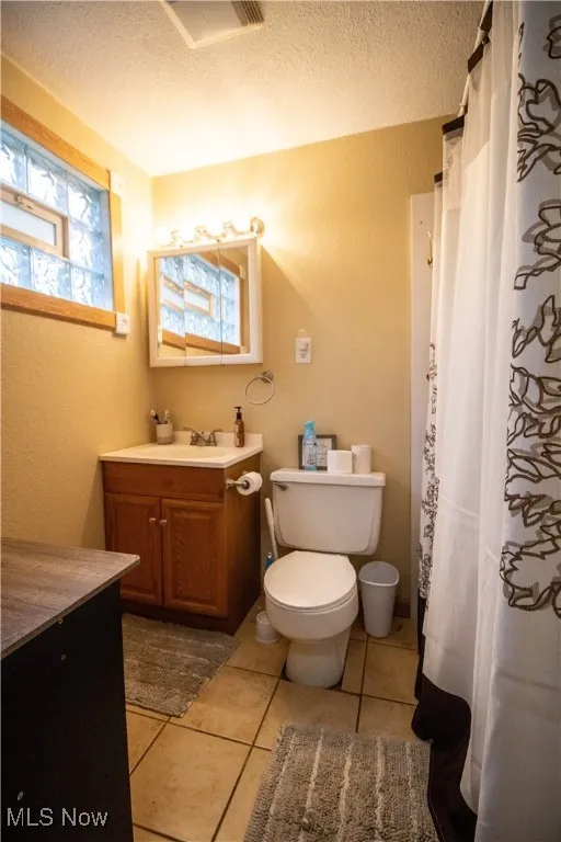 Full Master bathroom featuring vanity, tile patterned flooring, a textured ceiling, toilet, and curtained shower