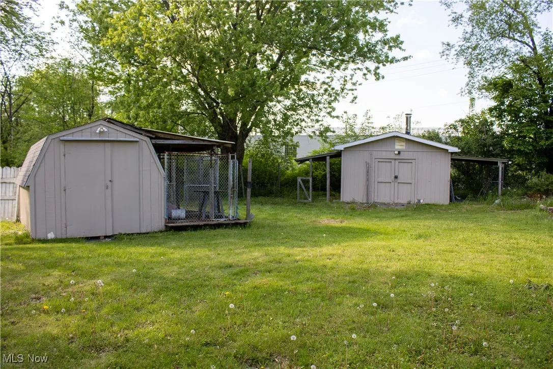 View of green lawn featuring a storage shed and an outbuilding
