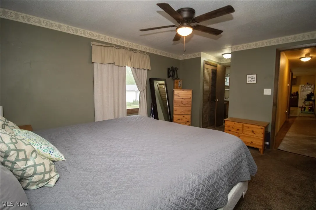 Carpeted bedroom with a closet and a ceiling fan